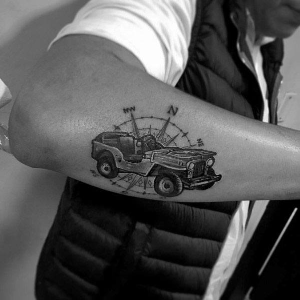 Black and grey tattoo of a classic Jeep over a detailed compass design, symbolizing adventure, exploration, and off-road freedom.