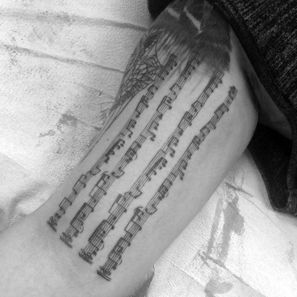 Tattoo featuring detailed musical notes arranged in flowing vertical lines, creating a striking design that represents a deep connection to music.