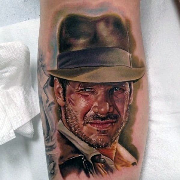 Hyper-realistic Indiana Jones tattoo featuring his rugged expression, iconic fedora, and detailed shading for a lifelike effect.