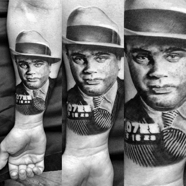 Al Capone tattoo sleeve featuring a detailed black-and-white portrait of the gangster with his inmate number "0727 16 29" visible, and his signature fedora.