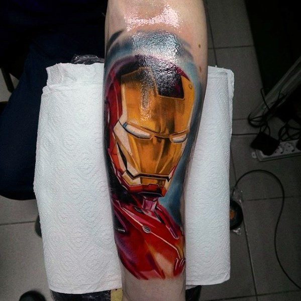 Iron Man tattoo featuring a vivid, high-detail depiction of his helmet with glowing eyes, showcasing rich red and gold tones and dramatic shading on the forearm.
