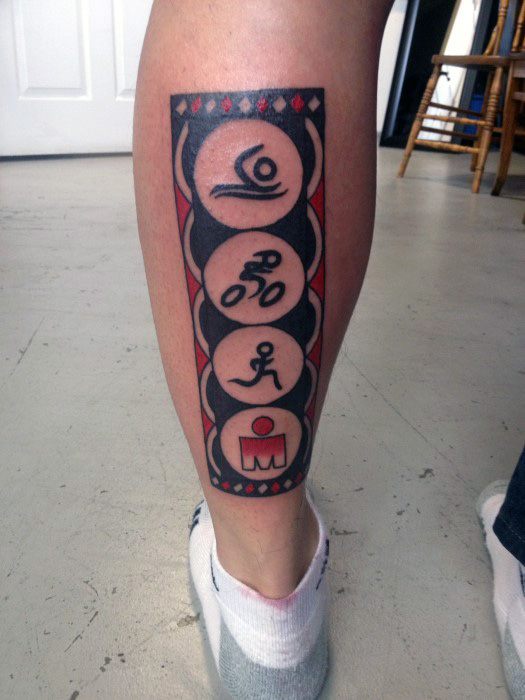 Vertical tattoo on the calf featuring swim, bike, and run icons stacked above a red Ironman logo, framed with bold black and red geometric borders.