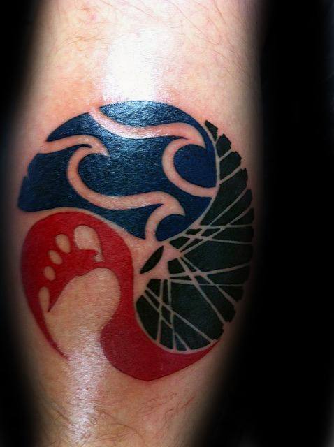 Abstract Ironman-themed tattoo combining a swimmer, bike wheel, and foot in a yin-yang-inspired circular design with bold red, black, and blue tones.