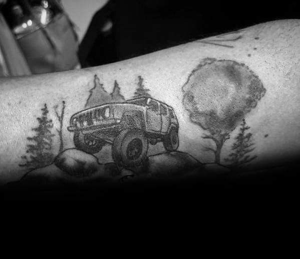 Black and grey tattoo of a lifted Jeep navigating rocky terrain, surrounded by trees and a full moon, capturing an adventurous off-road theme.