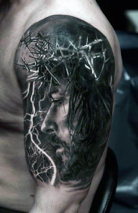 Realistic tattoo of Jesus Christ with a crown of thorns, highlighted by dramatic lightning and shadow effects on the upper arm