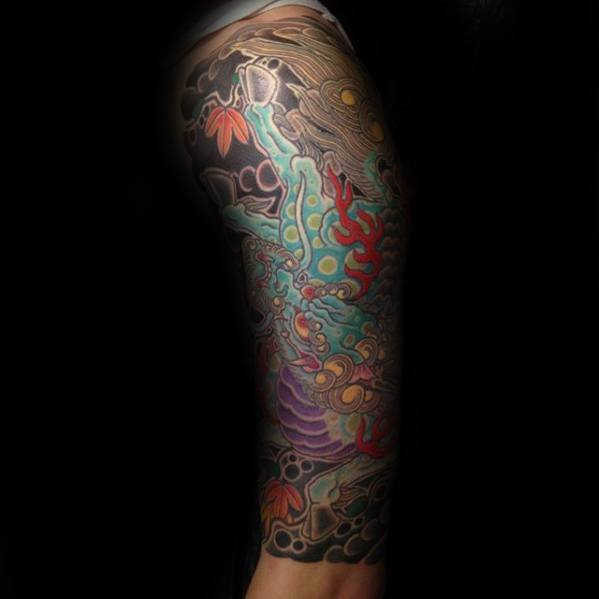 Colorful full-leg Kirin tattoo with turquoise body, red flames, and vibrant floral and wave elements in a dynamic Japanese-style composition.