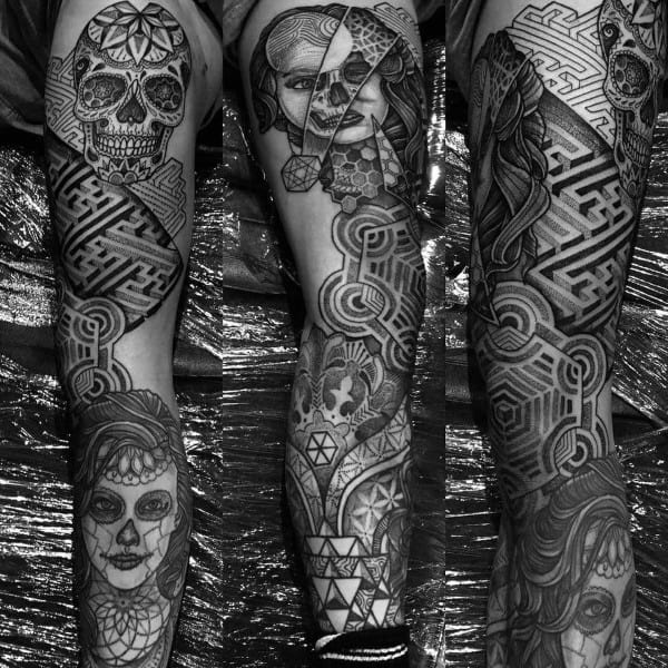 Intricate black and grey full-sleeve tattoo featuring labyrinth patterns, geometric shapes, skulls, and realistic portraits blended seamlessly.