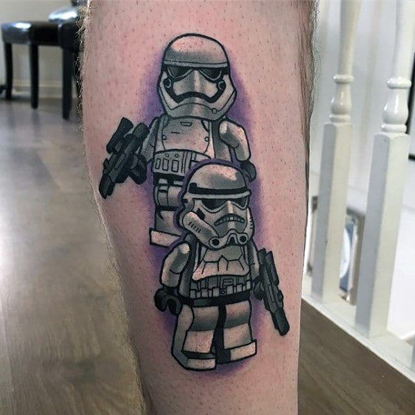 Tattoo of two Lego Stormtroopers, one classic and one modern, holding blasters with purple shading for contrast and depth on the leg.