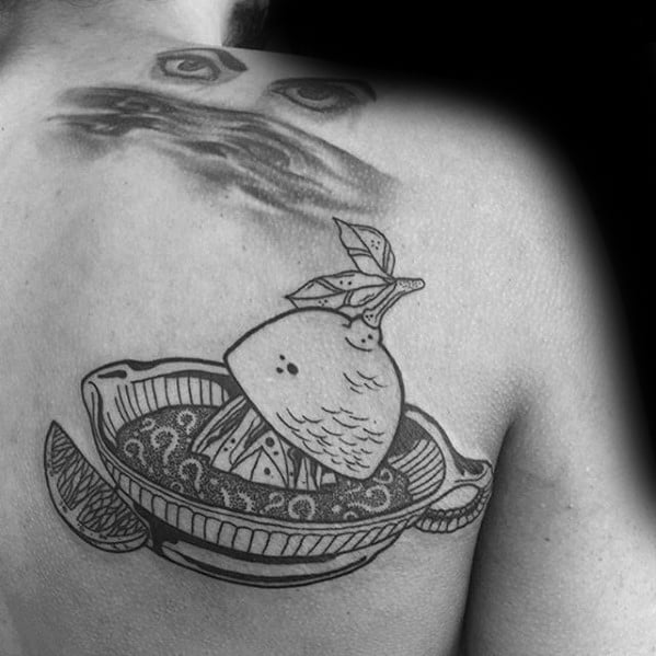 Blackwork tattoo of a lemon being juiced in a vintage-style citrus squeezer with fine line details and patterned juice inside the bowl.