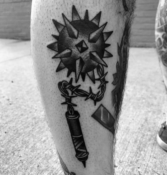 Black ink mace tattoo featuring a spiked ball connected by a barbed chain to a wrapped handle, symbolizing power, resilience, and medieval weaponry.