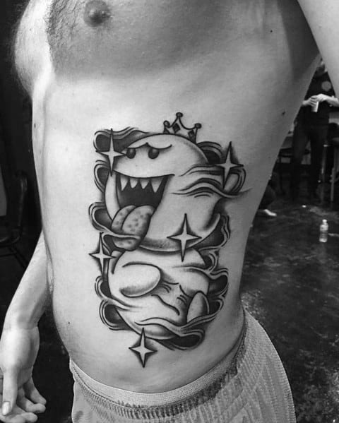 Large Mario ghost tattoo featuring King Boo with a crown, tongue out, and bold black and grey shading, inked on the ribcage with a dynamic design.