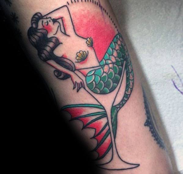Traditional-style martini glass tattoo featuring a mermaid with green scales and seashell details. A bold and vibrant nautical-inspired design.