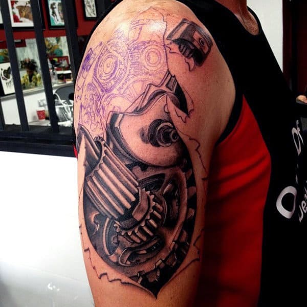 Tattoo of mechanical gears and pistons on an upper arm