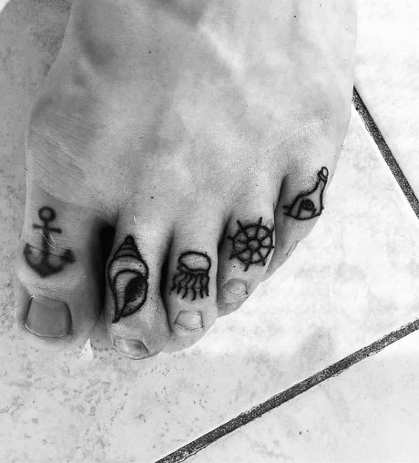 Minimalist nautical tattoos on toes featuring an anchor, seashell, jellyfish, ship wheel, and a message in a bottle