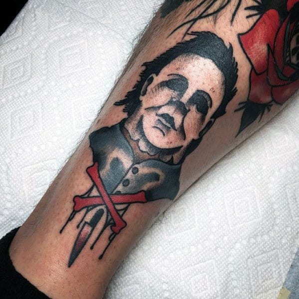 Traditional-style Michael Myers tattoo with bold lines, his eerie mask, and a crossed-out knife dripping with blood for a horror twist.