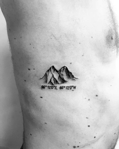 Minimalist mountain tattoo on the ribcage, featuring fine line peaks with subtle shading and geographic coordinates for a personal touch.