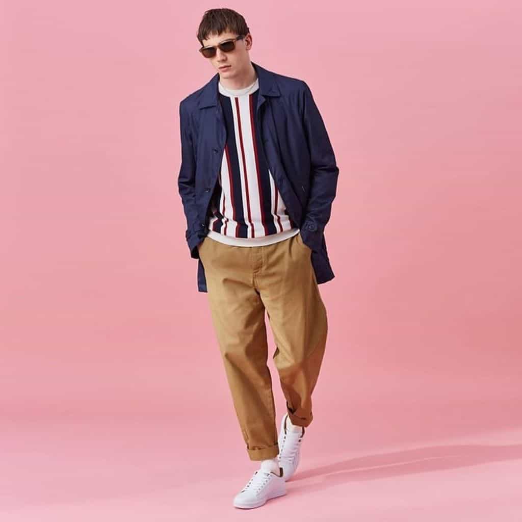 A male model wearing dark khaki-colored chinos rolled up at the ankle