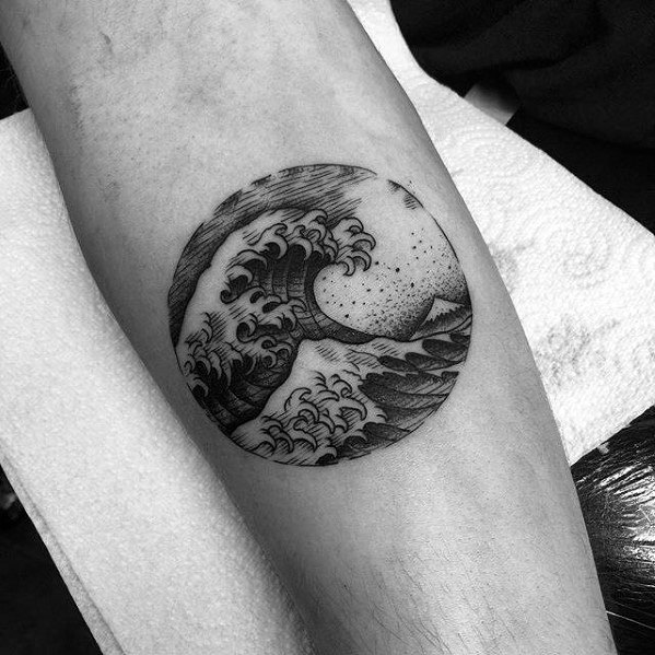 Black ink circular tattoo featuring a detailed crashing wave, a distant mountain, and a starry sky, blending Japanese and fine line art styles.