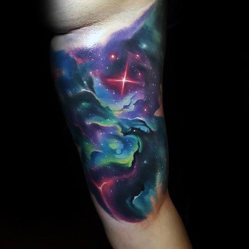 Nebula tattoo of vibrant stars graces an arm, set against a deep, dark backdrop