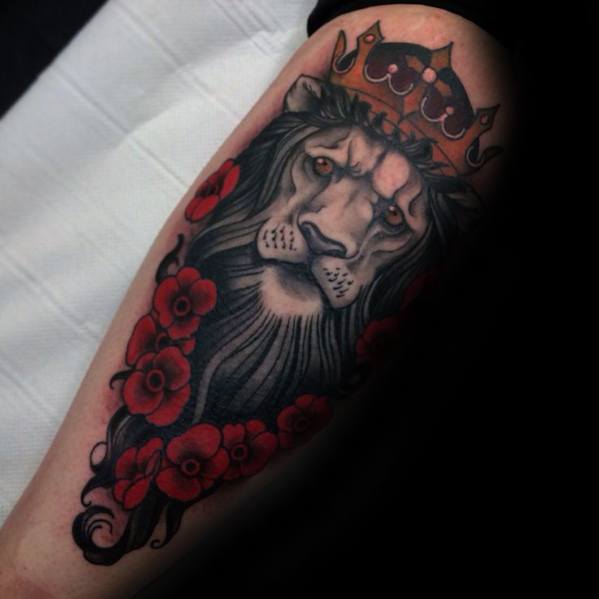 Neo-traditional lion tattoo with a crown, flowing black mane, and vivid red flowers for a regal and powerful forearm design.