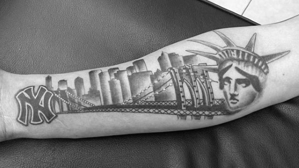 Black and gray forearm tattoo featuring the Statue of Liberty, NYC skyline, a bridge, and the New York Yankees logo.