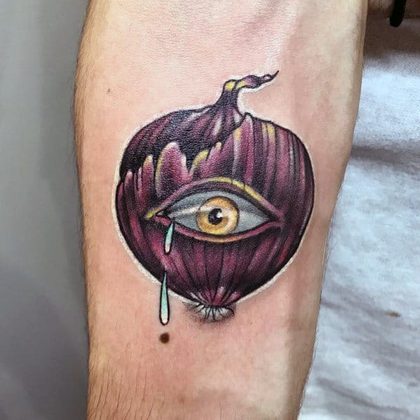 Surreal onion tattoo featuring a realistic human eye within a purple onion, shedding a tear, with detailed shading and vibrant colors.