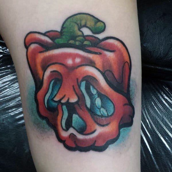 Red bell pepper tattoo with a skull-like hollowed-out design, featuring bold outlines and vibrant shading for a striking and eerie look.