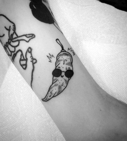 Playful black ink chili pepper tattoo with a smiling face and sunglasses, featuring simple linework for a fun and quirky design.
