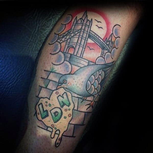 Colorful pigeon tattoo with Tower Bridge, graffiti-style “LDN” on cheese, and a sunset sky, celebrating London’s street culture.