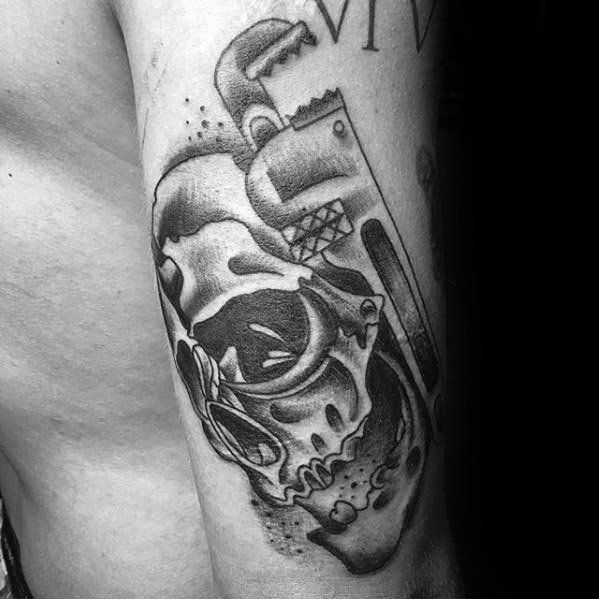 Black and grey tattoo of a detailed skull combined with a pipe wrench, blending realism with bold plumbing symbolism.