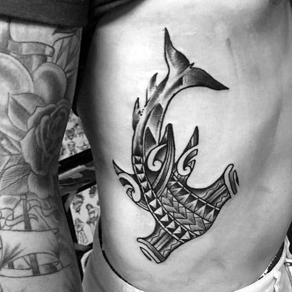 Polynesian hammerhead shark tattoo on side torso with detailed tribal patterns symbolizing power, protection, and deep cultural roots.