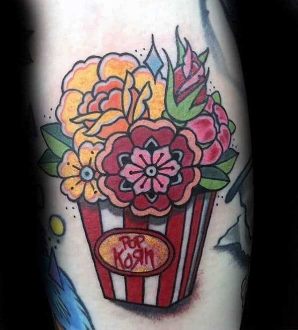 Tattoo of a red-striped popcorn box filled with colorful flowers instead of popcorn, blending floral and pop art elements.