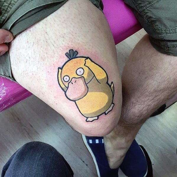 Large Psyduck tattoo with a classic confused expression, covering the upper thigh of a man in a bold cartoon style.