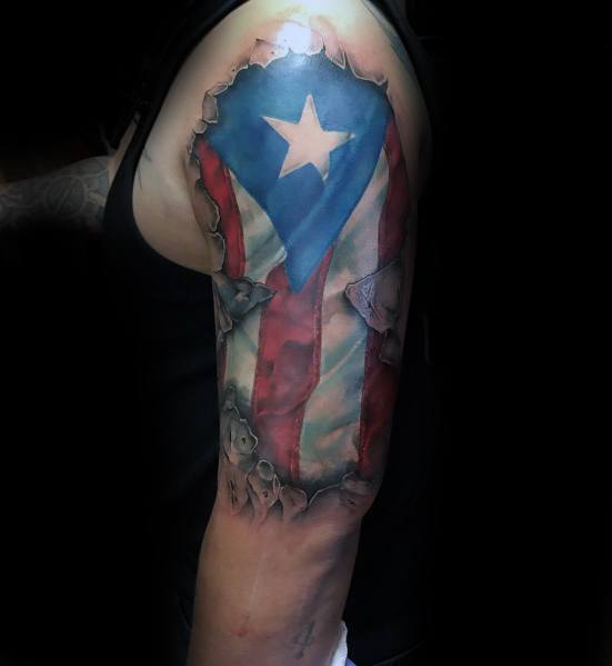 Puerto Rican flag tattoo with a realistic torn skin effect on the upper arm, revealing bold red, white, and blue colors with a striking star.