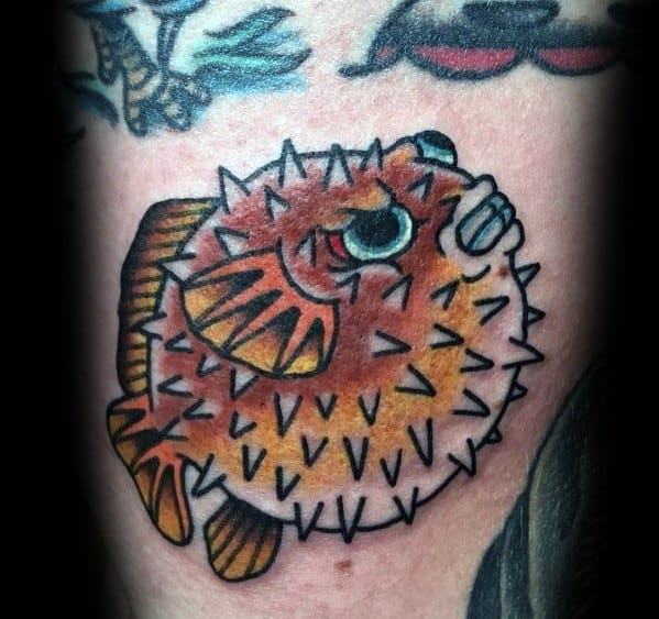 Traditional-style pufferfish tattoo with bold black outlines, vibrant orange shading, and sharp spines, creating a classic and dynamic look.