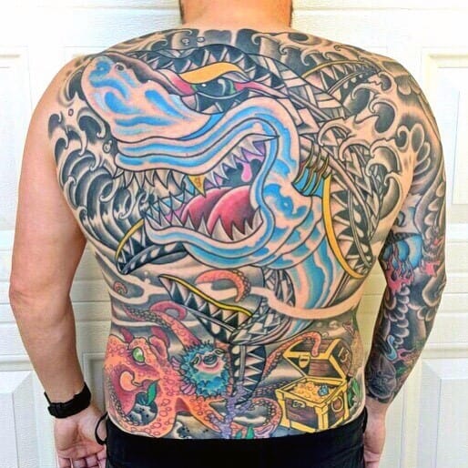 Full-back nautical tattoo featuring a fierce shark, octopus, pufferfish, and treasure chest, blending bold colors with intricate wave patterns.