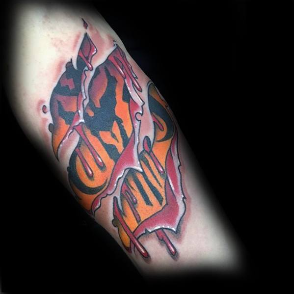 Tattoo of a torn skin effect revealing an orange and black Mandalorian Mythosaur skull with dripping edges and bold comic-style lines.