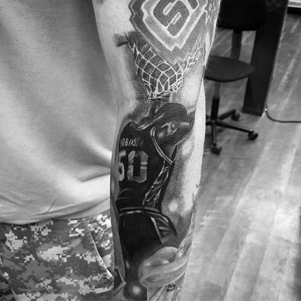 Realistic black and grey tattoo of San Antonio Spurs legend David Robinson (#50) dunking a basketball, with the team logo and net above.