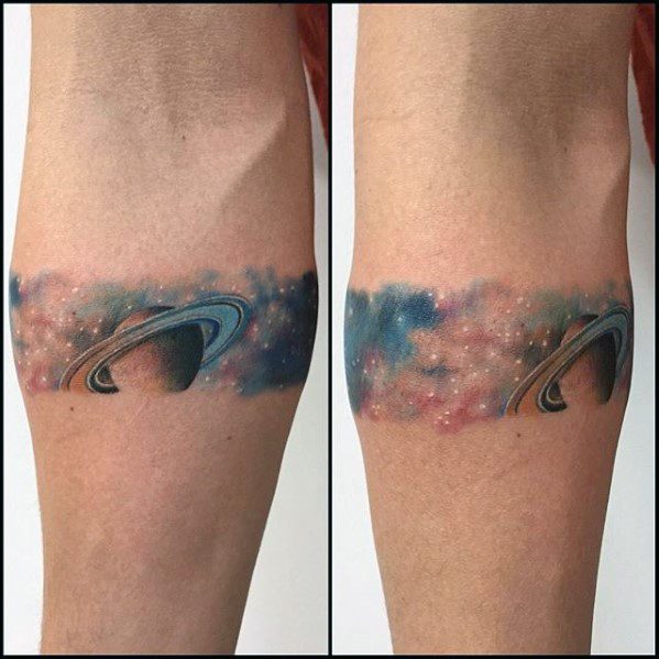 Colorful Saturn tattoo band for men wrapping around the arm, with a soft galaxy background in pink, blue, and purple tones.