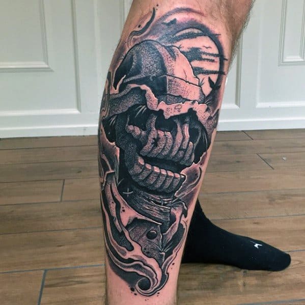 Bold scarecrow tattoo on the calf with a torn burlap mask, sharp teeth, swirling smoke, and intense shading in black and red tones.