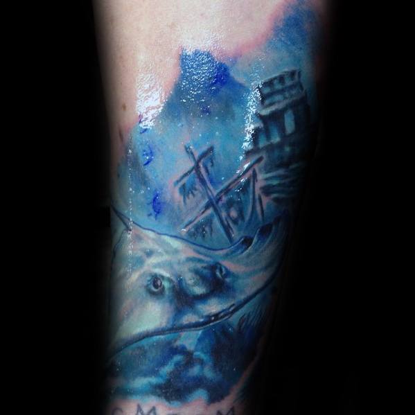 Moody blue-toned tattoo of a sunken ship near ancient ruins with a ghostly sea creature emerging from the deep water below.