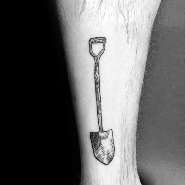 Minimalist black ink shovel tattoo with fine line detailing on the handle and blade, placed on the forearm for a simple yet bold design.
