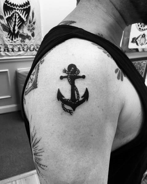 Bold black anchor tattoo with a rope detail on the upper arm, symbolizing strength, stability, and a deep connection to the sea.