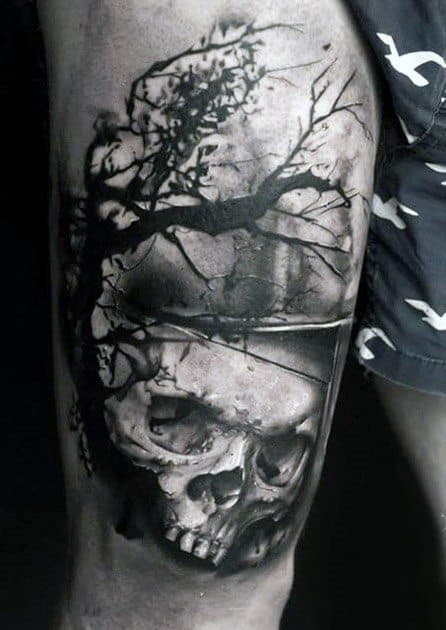 Dark thigh tattoo featuring a realistic skull beneath a shadowy tree with bare branches, creating a haunting and moody atmosphere.