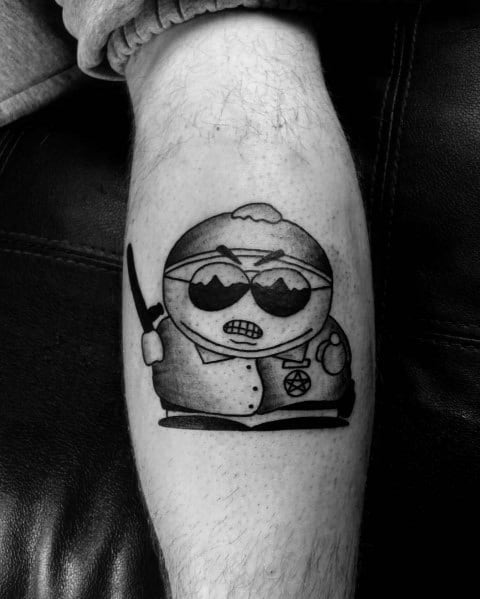 Black and white Cartman tattoo from South Park, featuring him in sunglasses, a bandage, and holding a knife for a bold, edgy look.