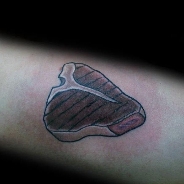 Tattoo of a grilled T-bone steak with sear marks, simple black outlines, and shading, creating a clean and bold meat-inspired design