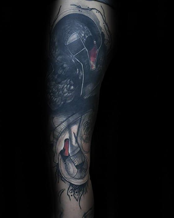Dark surreal swan tattoo featuring two black swans with red beaks, abstract elements, and fine linework creating a moody, artistic effect.