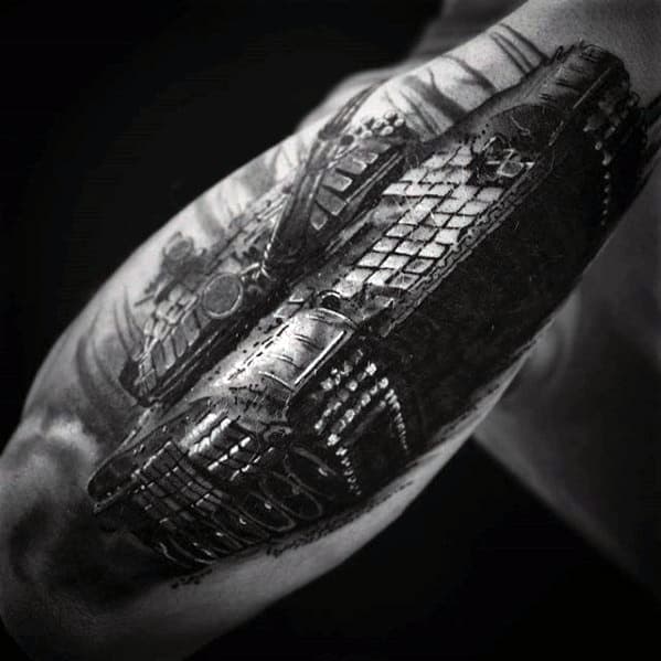 Realistic black and grey tattoo of a tank viewed from a dramatic low angle, showcasing heavy tread detail and intense shading.