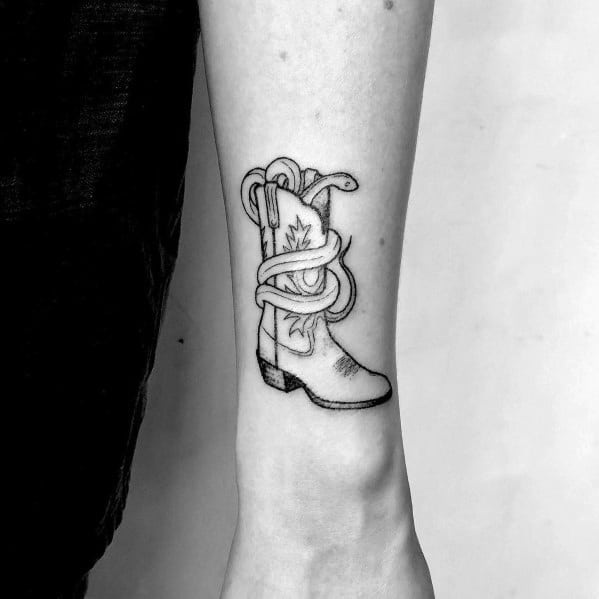 Minimalist black and white tattoo of a cowboy boot wrapped in a rope, featuring a leaf design, symbolizing Western heritage and resilience.
