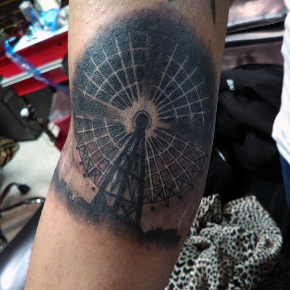 Realistic black and grey Ferris wheel tattoo with heavy shading and a dark, moody atmosphere, creating a striking and dramatic design.